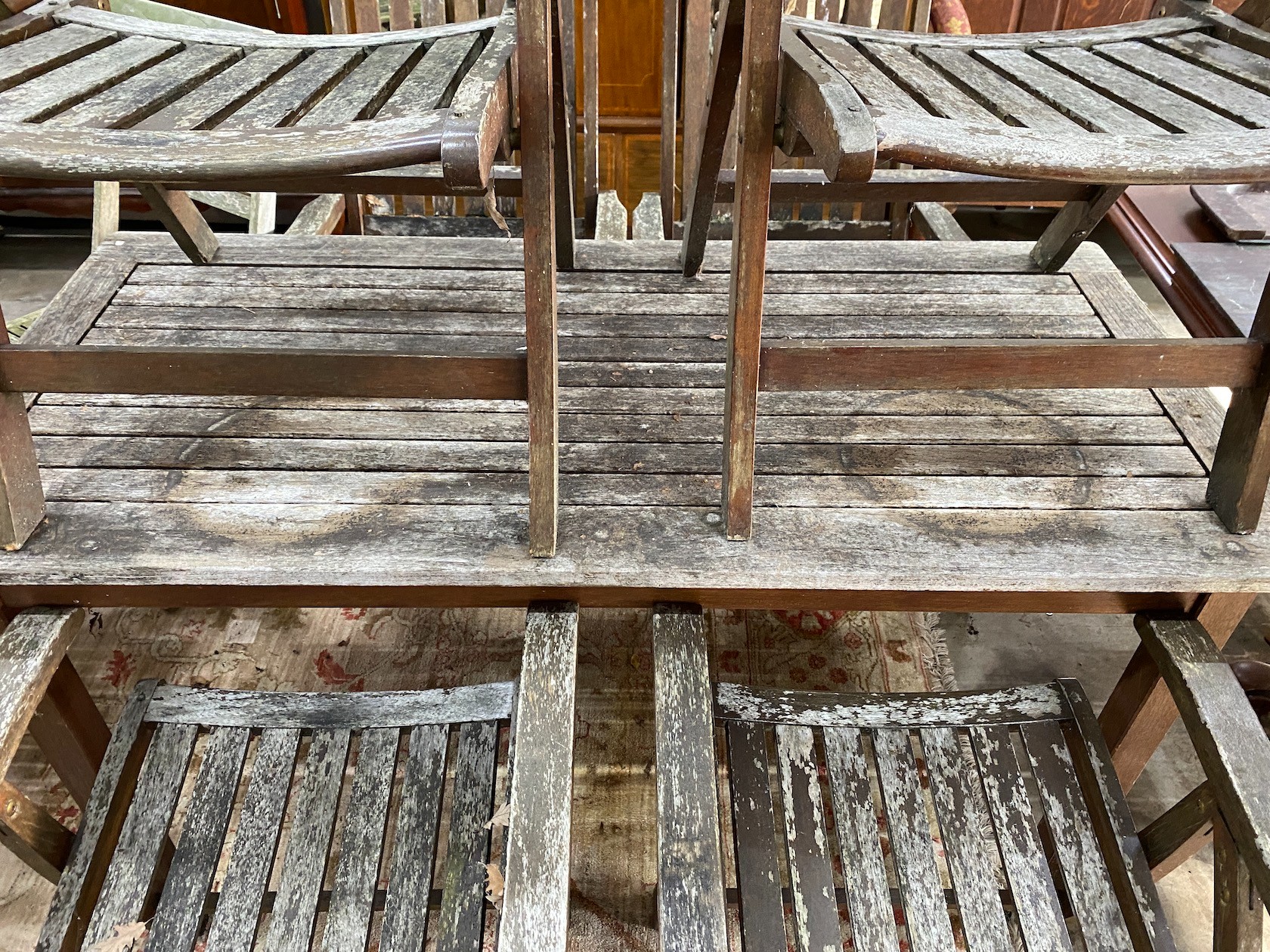 A rectangular weathered teak garden table, length 151cm, depth 70cm, height 73cm and six folding elbow chairs